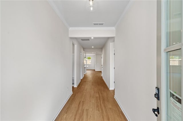 corridor featuring crown molding, baseboards, light wood-type flooring, and visible vents