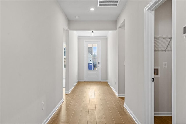 hallway featuring light wood-style floors, visible vents, and baseboards