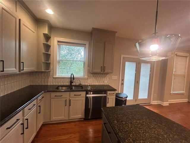 kitchen with backsplash, decorative light fixtures, dark stone counters, stainless steel dishwasher, and sink