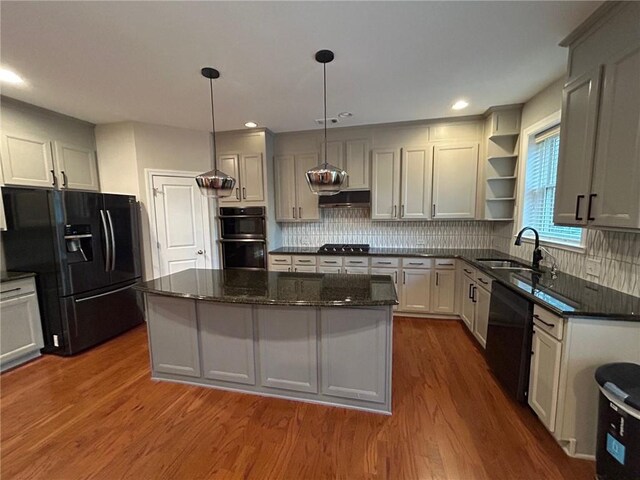 kitchen featuring hanging light fixtures, dark wood-type flooring, a kitchen island, black appliances, and sink