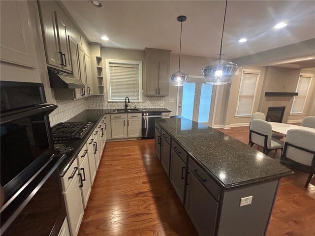 kitchen with dark hardwood / wood-style floors, tasteful backsplash, a kitchen island, stainless steel appliances, and decorative light fixtures