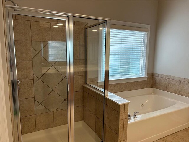 bathroom featuring plus walk in shower, plenty of natural light, and tile patterned flooring