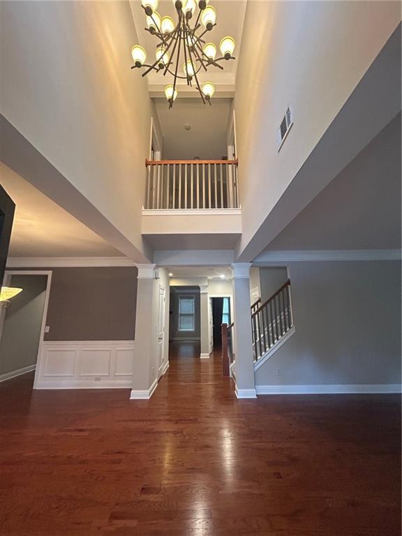 stairway featuring ornate columns, a high ceiling, hardwood / wood-style flooring, and crown molding