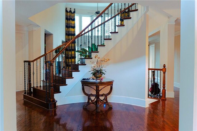 stairway with decorative columns, ceiling fan, hardwood / wood-style flooring, and ornamental molding