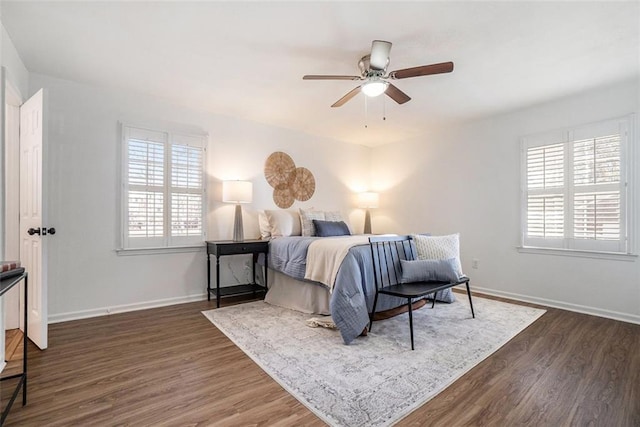 bedroom featuring ceiling fan, dark wood-type flooring, and multiple windows