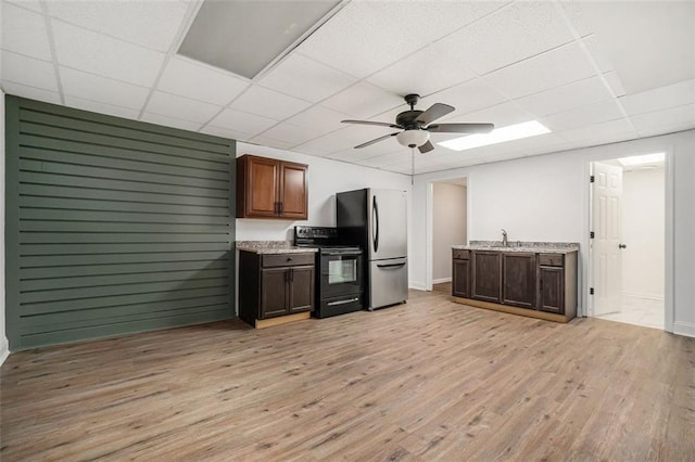 kitchen featuring black range with electric stovetop, sink, stainless steel refrigerator, a drop ceiling, and light hardwood / wood-style flooring