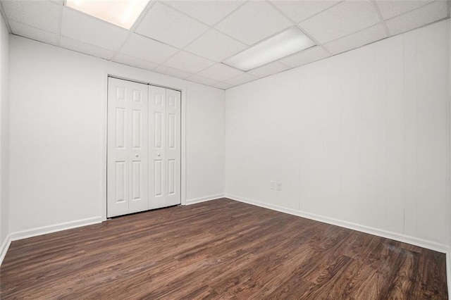 unfurnished bedroom featuring a closet, a paneled ceiling, and dark hardwood / wood-style floors