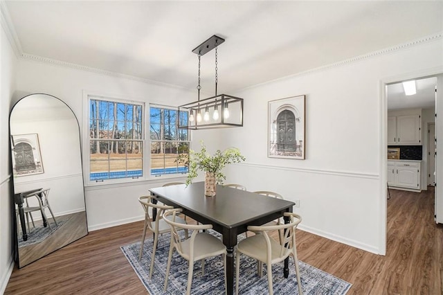 dining space featuring ornamental molding and dark wood-type flooring