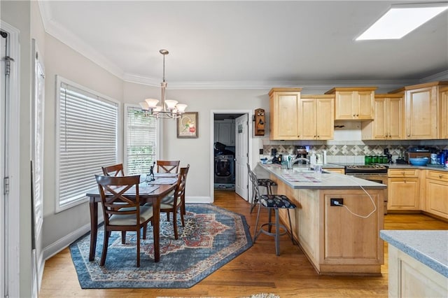 38 Olde Wick Trl, Hoschton, GA 30548 - kitchen featuring light brown cabinets, a chandelier, ornamental molding, a breakfast bar area, and decorative backsplash