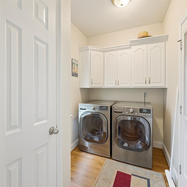 38 Olde Wick Trl, Hoschton, GA 30548 - laundry area featuring washing machine and clothes dryer, light wood finished floors, and cabinet space