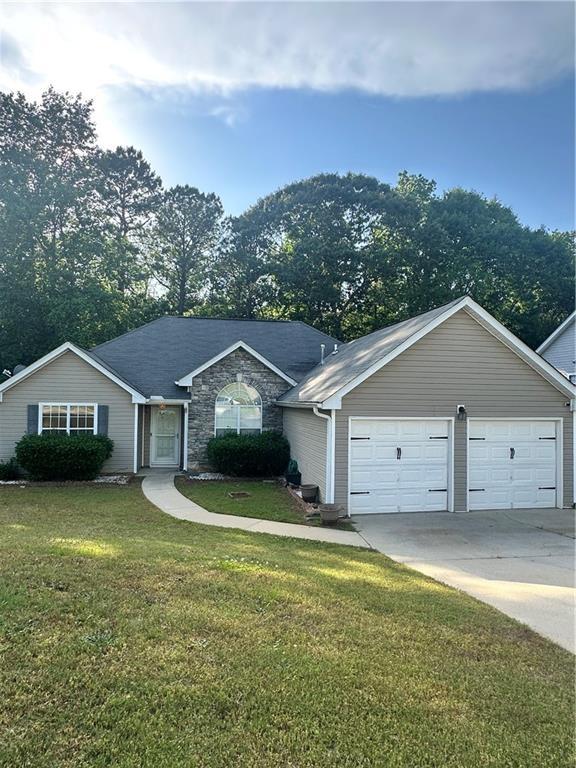 ranch-style home with concrete driveway, stone siding, and a front yard
