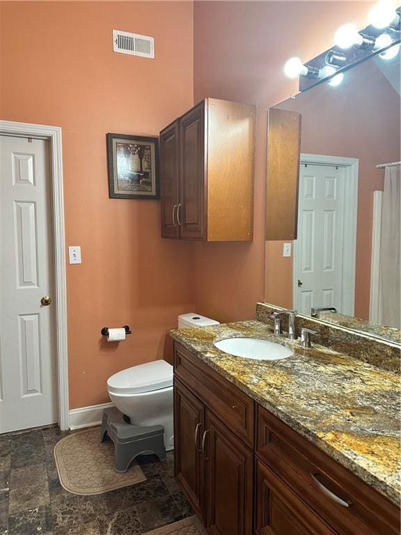 bathroom featuring visible vents, baseboards, vanity, toilet, and a high ceiling