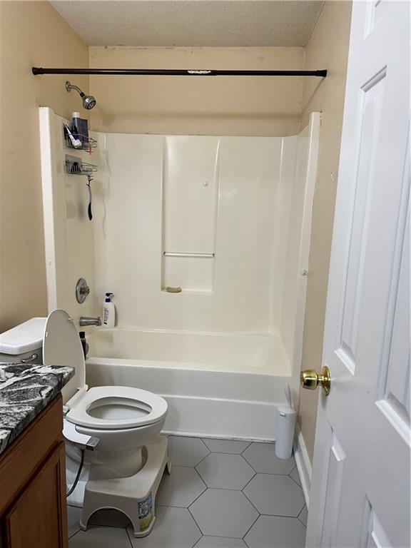 bathroom with vanity, a textured ceiling, toilet, and  shower combination