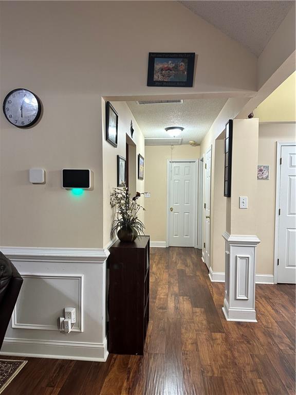 corridor with dark wood-type flooring and a textured ceiling