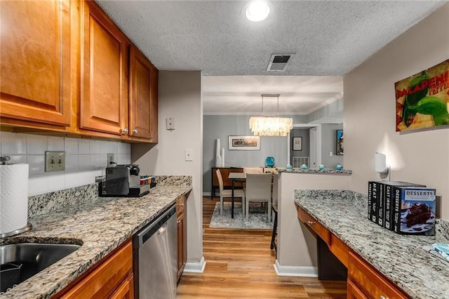 kitchen with an inviting chandelier, light stone counters, stainless steel dishwasher, a textured ceiling, and decorative light fixtures