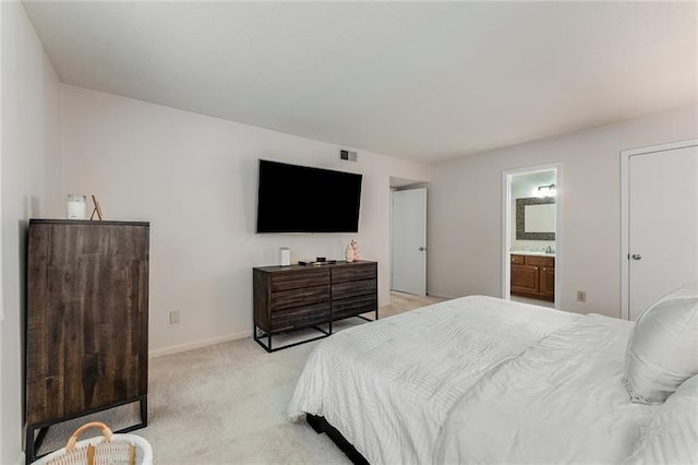 bedroom featuring ensuite bath and light carpet