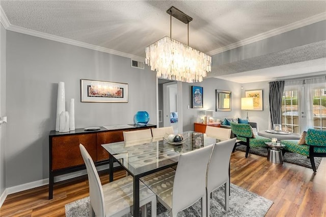 dining space with french doors, a chandelier, a textured ceiling, hardwood / wood-style flooring, and ornamental molding