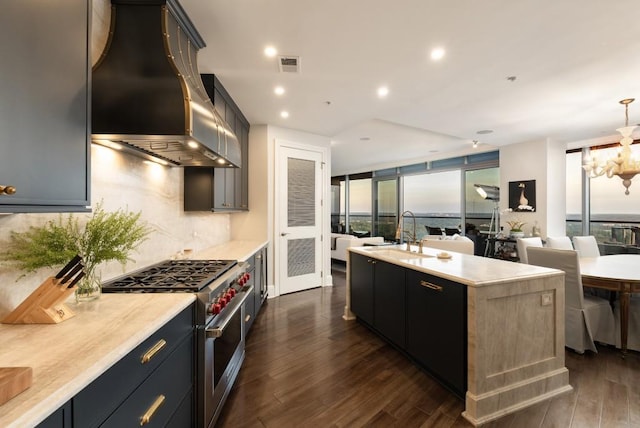 kitchen with a chandelier, wall chimney exhaust hood, high end stove, open floor plan, and visible vents