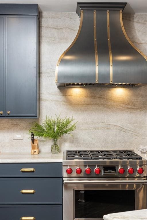 kitchen featuring light countertops, gray cabinetry, stainless steel stove, and custom range hood