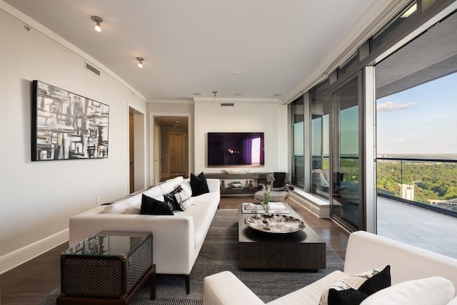 living area featuring visible vents, ornamental molding, baseboards, and wood finished floors