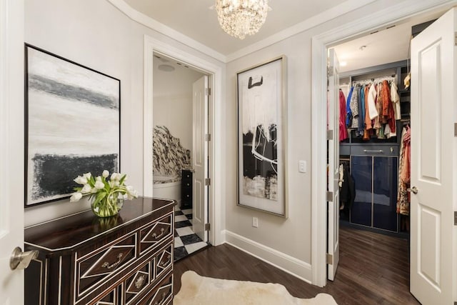 corridor featuring baseboards, ornamental molding, a notable chandelier, and dark wood-style floors