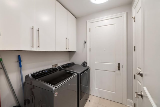 laundry area with cabinet space, separate washer and dryer, and light tile patterned floors