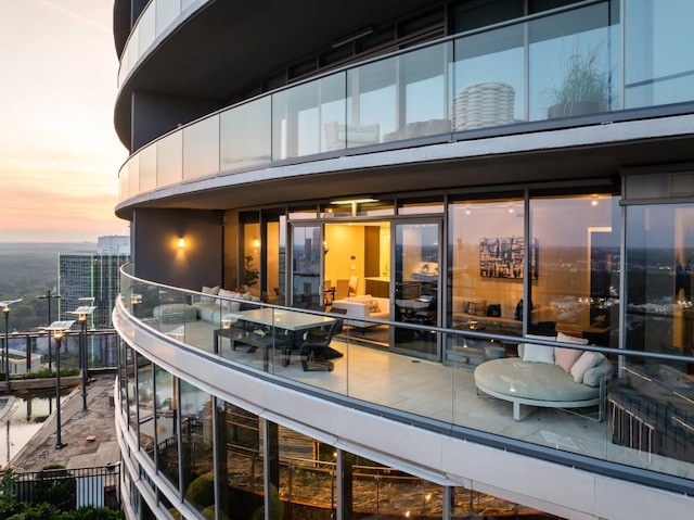 back of property at dusk featuring a view of city and a balcony