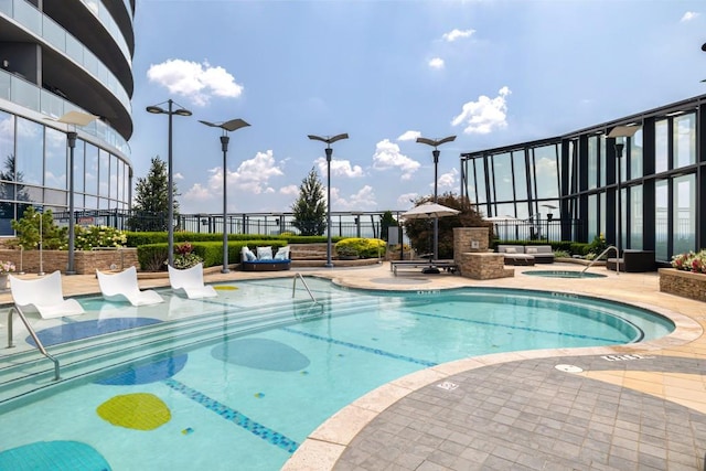 community pool with a patio, a hot tub, and fence