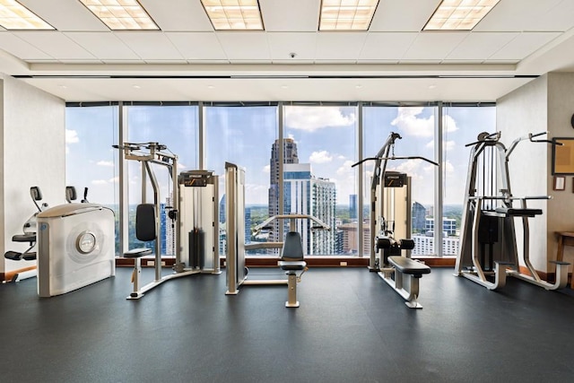 workout area featuring a paneled ceiling, a city view, and expansive windows