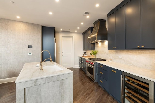 kitchen featuring a sink, beverage cooler, wall chimney exhaust hood, high end range, and baseboards