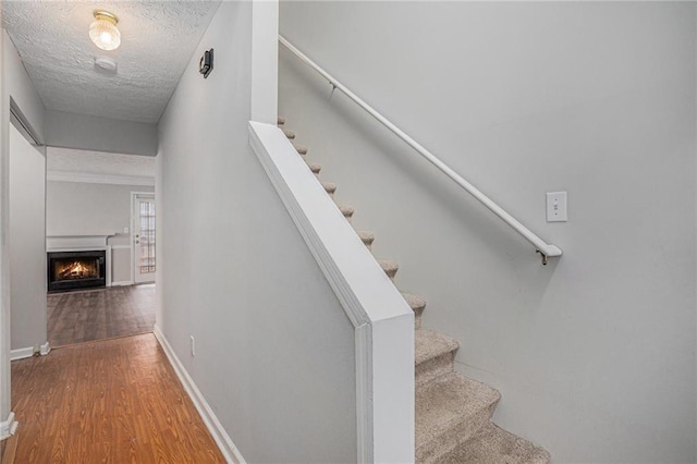 stairway with hardwood / wood-style flooring and a textured ceiling