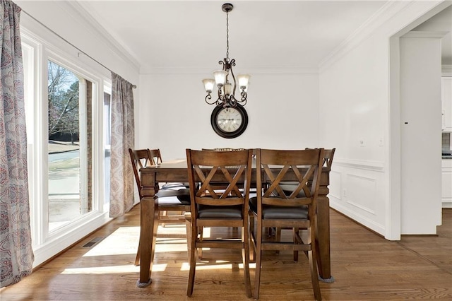 dining area featuring dark hardwood / wood-style floors, crown molding, and a notable chandelier