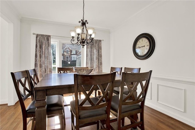 dining space with crown molding, an inviting chandelier, and wood-type flooring