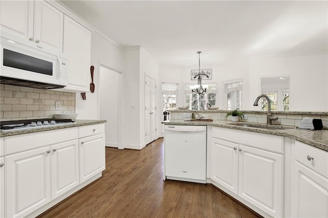 kitchen featuring hanging light fixtures, white appliances, light stone counters, sink, and white cabinetry