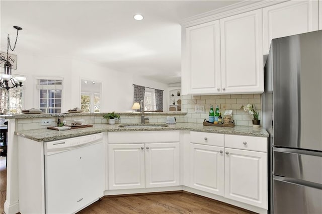 kitchen with dishwasher, stainless steel refrigerator, sink, white cabinetry, and kitchen peninsula