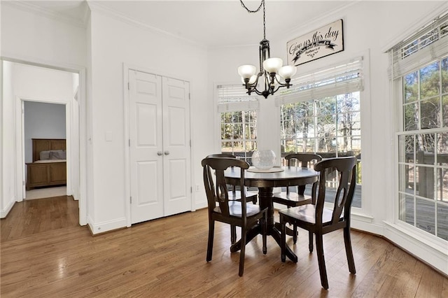 dining space with ornamental molding, hardwood / wood-style floors, and an inviting chandelier