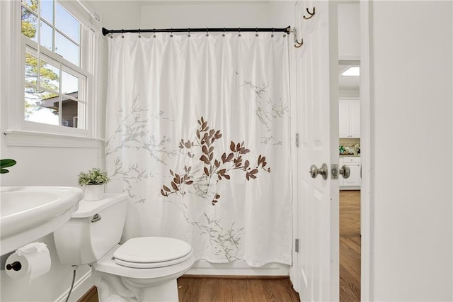bathroom with toilet, shower / bathtub combination with curtain, washer / dryer, and wood-type flooring