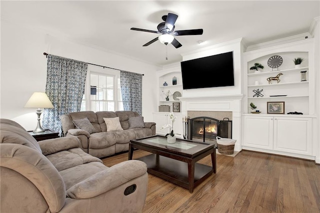 living room featuring wood-type flooring, built in features, and ornamental molding