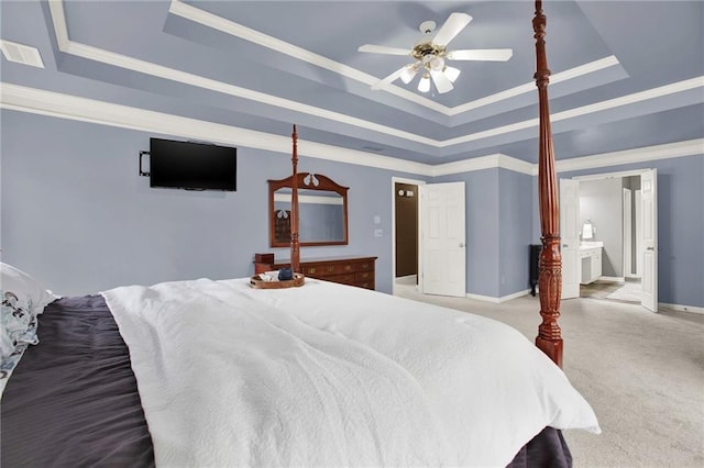 carpeted bedroom with a raised ceiling, ceiling fan, crown molding, and connected bathroom