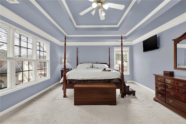 carpeted bedroom featuring a raised ceiling, multiple windows, and ceiling fan