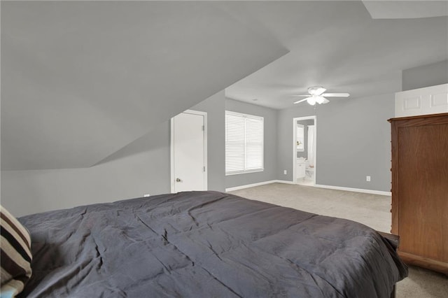 unfurnished bedroom with ensuite bath, ceiling fan, vaulted ceiling, and light colored carpet