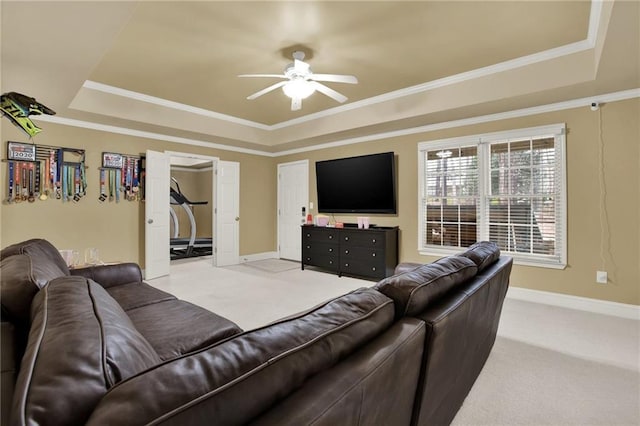 living room featuring ornamental molding, light carpet, ceiling fan, and a raised ceiling