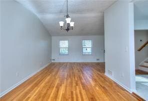 interior space with baseboards, stairs, lofted ceiling, an inviting chandelier, and wood finished floors