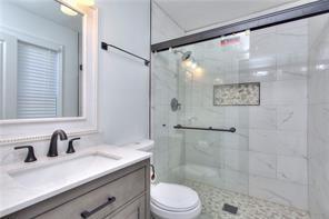 full bath featuring toilet, vanity, and a tile shower