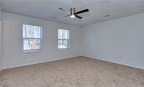 carpeted spare room with a ceiling fan and baseboards