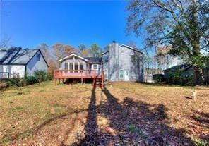 rear view of house featuring a deck, a lawn, and a chimney