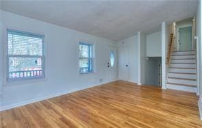 unfurnished living room featuring light wood-style floors and stairs