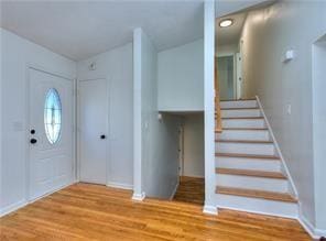 foyer with stairway, baseboards, and wood finished floors