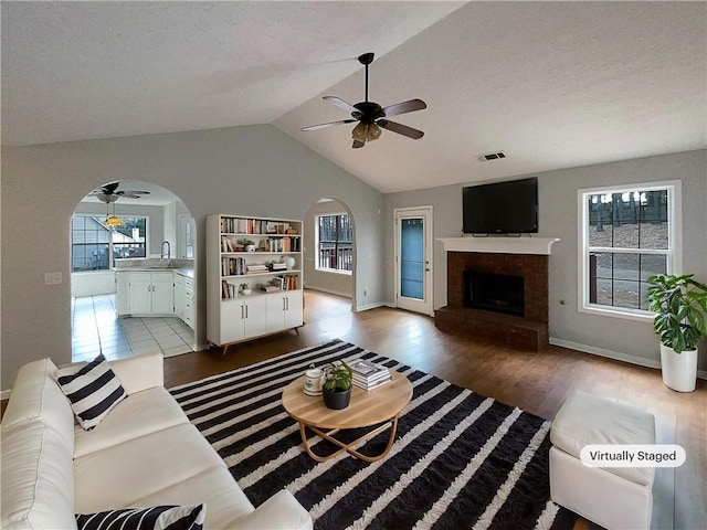 living room featuring sink, a fireplace, ceiling fan, and light wood-type flooring