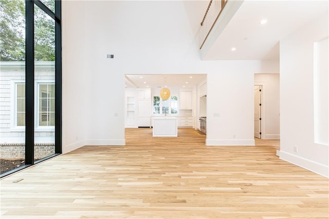 unfurnished living room with a towering ceiling and light hardwood / wood-style floors